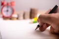 Man`s hand with pencil writing on notebook.