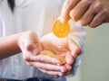 A man`s hand picked up a gold bitcoin coin from a woman`s palm