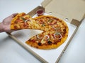 A man`s hand is picking a pizza from the pizza tray