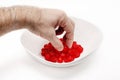 Man's hand picks a cherry from a white bowl with delicious red dried cherries. White background Royalty Free Stock Photo