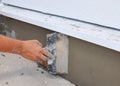 Man's hand plastering a wall insulation and house foundation with trowel. Royalty Free Stock Photo