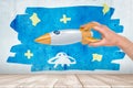 Man`s hand playing with silver and orange space rocket against wall with sketchy painting of blue starry sky and small Royalty Free Stock Photo