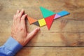 Man's hand pointing at plane made from tangram puzzle Royalty Free Stock Photo