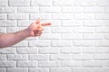 Man`s hand pointing on white brick wall background Royalty Free Stock Photo