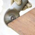 Man's hand polishing wooden board by saw machine.