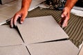man's hand positioning large ceramic floor tile during flooring installation