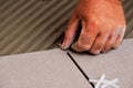 man's hand positioning plastic spacer during ceramic floor tile installation.