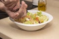 A man`s hand pouring black pepper into a mixed salad. Royalty Free Stock Photo