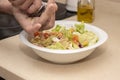 A man`s hand pouring black pepper into a mixed salad. Royalty Free Stock Photo