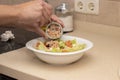 A man`s hand pouring a can of tuna on top of a mixed salad. Royalty Free Stock Photo