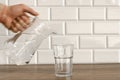 A man's hand pouring fresh pure water from bottle into a glass on the table, health and diet concept Royalty Free Stock Photo