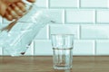 A man's hand pouring fresh pure water from bottle into a glass on the table, health and diet concept Royalty Free Stock Photo