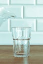 A man's hand pouring fresh pure water from bottle into a glass on the table, health and diet concept Royalty Free Stock Photo