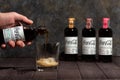 ManÃ¢â¬â¢s hand pouring Herbal Coca-Cola from bottle to ice-filled double old fashioned glass