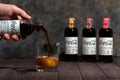 ManÃ¢â¬â¢s hand pouring Herbal Coca-Cola from bottle to ice-filled double old fashioned glass