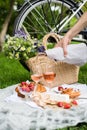 Man`s hand pouring rose wine into glasses, summer picnic