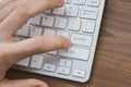 Man`s hand pressing enter button on wireless keyboard on wooden table Royalty Free Stock Photo