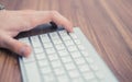 Man`s hand pressing escape button on wireless keyboard on wooden table Royalty Free Stock Photo