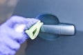 Man`s hand in protective gloves cleaning car door handle using antibacterial or cleaning solution Royalty Free Stock Photo