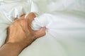 The man`s hand pulled the white sheets, Hand mauled the white sheets on the bed, hands of a doctor with patient in the hospital.