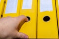 A man`s hand pulls out a binder folder from the storage shelf. Office worker finding a folder in the archive. Database,