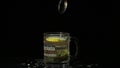 Man`s hand put a glass cup with Green tea. Glass cup with organic dry green tea leaves and slice of lemon which are floating insid