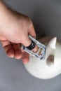 A man`s hand puts a hundred dollars in a gray piggy bank. Ceramic piggy bank in the shape of a cat. The thumb is wrapped with Royalty Free Stock Photo