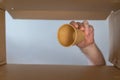 A Man`s Hand Puts A Paper Cup In A Cardboard Moving Box. Disposable Drink Glass. Bottom View. Inside View. Close-up. Selective