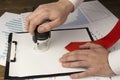 A man`s hand puts a seal on a blank sheet, a tie, a magnifying glass print