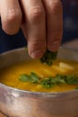 Man`s hand putting green spices into soup. Man hand eating fresh spices with traditional Colombian dish