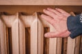 Man's hand and radiator, close-up. Man warming his hand over a heater