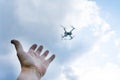 The man`s hand reaches for the flying drone. The drone is out of focus.