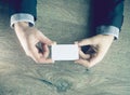 Man`s hand showing business card - closeup shot on dark wooden background Royalty Free Stock Photo