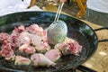 Man`s hand with skimmer turning over chicken meat frying in sizzling olive oil in large flat pan. Cooking Spanish paella