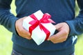 Man`s hand with a small white gift box with bow