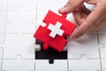 Man`s hand solving jigsaw puzzle with red piece Royalty Free Stock Photo