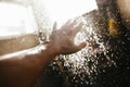 A man`s hand in a spray of water in the sunlight against a dark background. Water as a symbol of purity and life Royalty Free Stock Photo