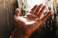 A man`s hand in a spray of water in the sunlight against a dark background. Water as a symbol of purity and life Royalty Free Stock Photo