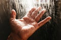 A man`s hand in a spray of water in the sunlight against a dark background. Water as a symbol of purity and life Royalty Free Stock Photo