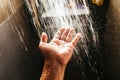 A man`s hand in a spray of water in the sunlight against a dark background. Water as a symbol of purity and life Royalty Free Stock Photo