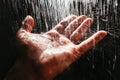 A man`s hand in a spray of water in the sunlight against a dark background. Water as a symbol of purity and life Royalty Free Stock Photo