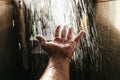 A man`s hand in a spray of water in the sunlight against a dark background. Water as a symbol of purity and life Royalty Free Stock Photo