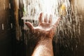 A man`s hand in a spray of water in the sunlight against a dark background. Water as a symbol of purity and life Royalty Free Stock Photo