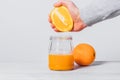 Man's hand squeeze orange juice into glass jar