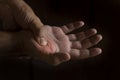 A man`s hand squeezing the metacarpus of the thumb. Joint pain in the right hand. Black background