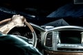 A man`s hand on the steering wheel of a car that moves along a night road among the mountains Royalty Free Stock Photo