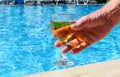 Man`s hand takes a glass of white wine by the pool. Royalty Free Stock Photo