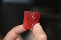 Man`s hand takes a red slice of strawberry marmalade on black background. Sweet food sugar concept