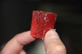 Man`s hand takes a red slice of strawberry marmalade on black background. Sweet food sugar concept