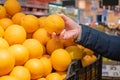 A man`s hand takes a ripe orange from a box with oranges in a supermarket. Royalty Free Stock Photo